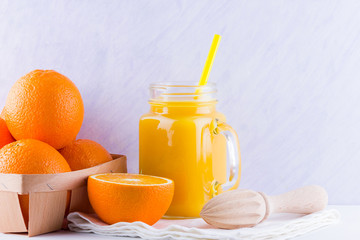 Orange fruits and juice on white background. Citrus fruit for making juice with manual juicer. Oranges in wooden box on white napkin. Mason jar with orange juice