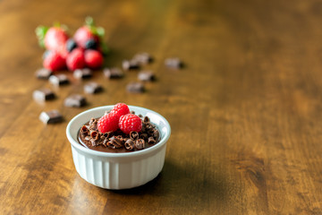 A decadent Chocolate Mousse Cake with chocolate ganache and topped with Raspberries, Blackberries and chocolate curls in a ramekin