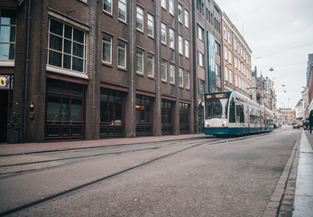 Fototapeta na wymiar Modern public transport in Amsterdam, Netherlands. White and blue tram in old city.