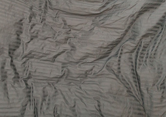 Wrinkled, grey bedsheets seen from above