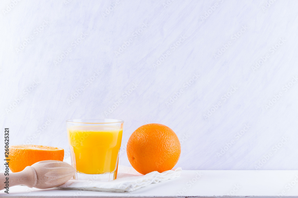 Wall mural Orange fruits with juice, concept. Orange juice and halves of oranges on white background. Citrus for making juice and manual juicer. Whole and squeezed oranges and glass of juice