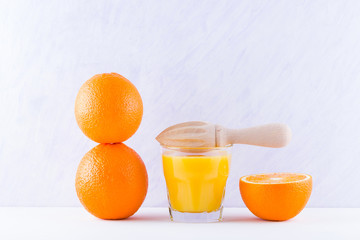 Orange fruits with juice, concept. Orange juice and halves of oranges on white background. Citrus for making juice and manual juicer. Whole and squeezed oranges and glass of juice