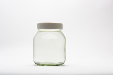 Empty glass jar lit in a studio with white background.