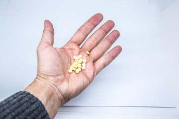 Medicine pills or capsules in elder hand