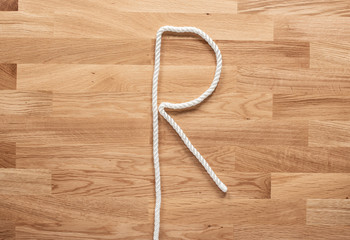 The letter R formed with white rope on a wooden table