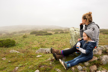 A mother and daughter resting and snacking during a hike.