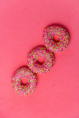 Row of donut on pimk background. Photo of sweets. Top view.