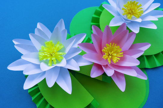 Waterlily flower made of paper. Blue background. Origami hobby. Gentle petal.
