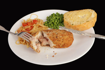 Chicken cordon bleu on white plate with pasta salad and green peas on Black BG