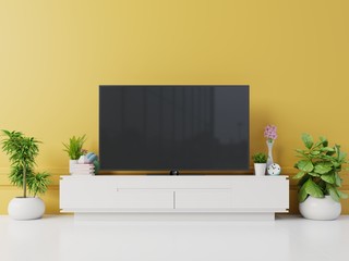 TV on cabinet in modern living room with lamp,table,flower and plant on yellow wall background,3d rendering