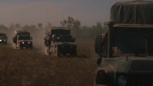 Military jeep convoy driving on an open field