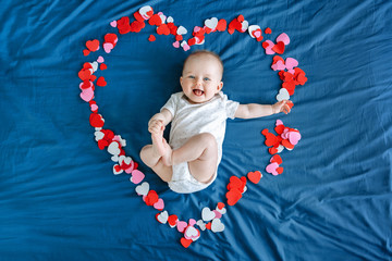 Cute smiling white Caucasian baby girl boy infant with blue eyes four months old lying on bed among...