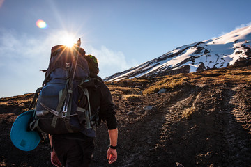 The way to the top. Man climbing a volcano. Hiker preparing to climb to the top of a volcano. Snowy mountain ahead the trekker path.