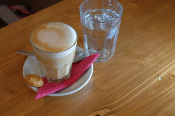 Coffee cup on table on sourcer with spoon and cookie angle view