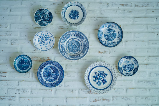 Ancient dish hang on white brick wall.