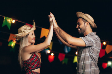 Brazilian couple wearing traditional clothes for Festa Junina - June festival - dancing under the...