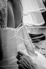 Mother of the bride helps her daughter to dress dresses, lace up a corset. Black and white photo.