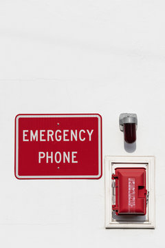 Red Emergency Phone Box On White Wall With Light And Sign Above Outside