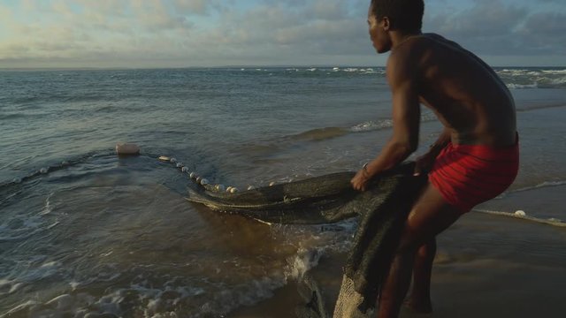4K view of two Subsistence fisherman working a seine net in the shallow surf, Mozambique