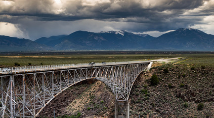 Rio Grande Gorge Bridge near Taos, New Mexico with stormy skies over the mountains.