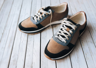 A pair of new suede sneakers on a rustic wooden background. The concept of jog and sports shoes. Copy space.