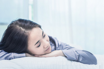 Asian woman sleep on  white pillow on bed in bedroom in holiday.happy relax time.color tone