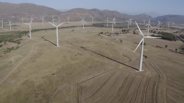 4K wide angle scenic aerial view of wind turbines turning on a wind farm