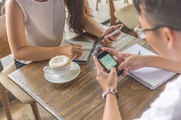 Young employee using smartphone and writing notes