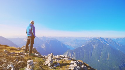 Fototapeta premium Traveler man relaxing standing and enjoying serene view mountains and lake landscape. Travel Lifestyle hiking concept spring autumn vacations outdoor. Austria Alps Dachstein Krippenstein five fingers