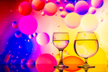 transparent glasses with water and oily drops on colorful background 