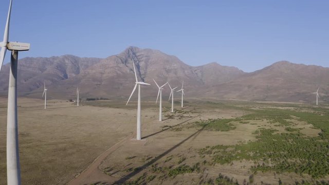 4K aerial scenic view of wind turbines turning on a wind farm