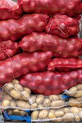 Bags with onion and potato at farmers market. Closeup fresh harvested potatoes and onions