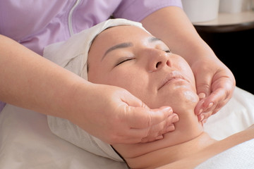 Cosmetic massage against the second chin. The technician is massaging female face at beauty salon. Spa procedures. Relaxation.