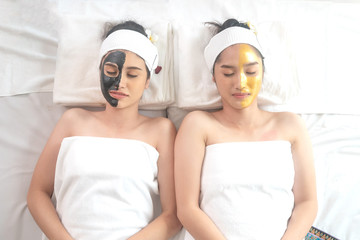 beautiful and healthy young woman relaxing with face massage skin care health black mask and gold mask at beauty spa salon