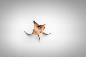 Woman looking out from a hole of torn paper