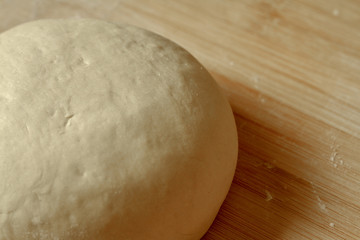 Fresh prepared dough on a bamboo board wheat flour close up