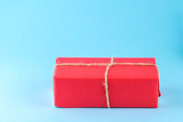 Red gift box tied with string on a bright blue background, minimalism.