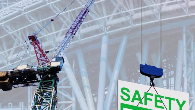  footage vdo.  of tower crane lifting a green wording  safety first signage panel with a big pylon and truss background