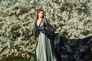 Fototapeta premium Portrait of a young beautiful fashionable woman in an evening dress . Girl posing in a blooming garden
