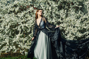 Fototapeta premium Portrait of a young beautiful fashionable woman in an evening dress . Girl posing in a blooming garden