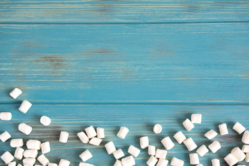 Background for banner with marshmallows on a blue wooden background. Background with sweets. Background design for cafe, sweet shop