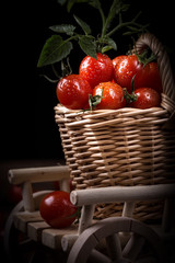 Juicy red tomatoes in basket on wooden table, closeup