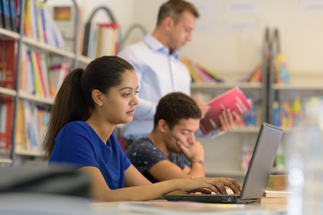 students doing research in the campus library