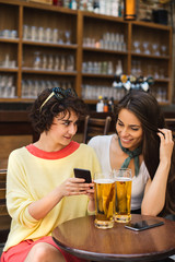 Two girls chatting while having a beer. Long haired and short haired girl drinking beer. 