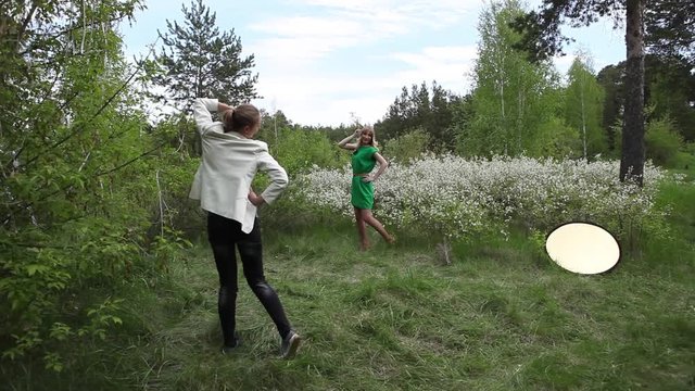the photographer takes pictures of the model in a dress among the green forest