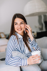 Girl at home using her phone. Woman talking on the phone, sits at home. 