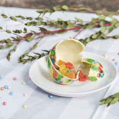 Easter eggs of white chocolate handmade on the table decorated with satin ribbons, green branches, willow on gray background.