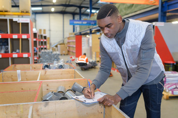 worker filling in paperwork on clipboard in plumbing hardware store