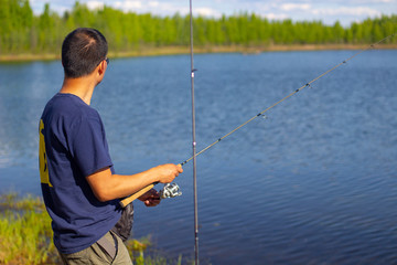 A fishing man standing on a lake shore