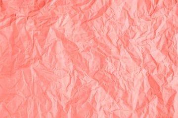Fototapeta premium Wrinkled paper texture background in trendy coral color.